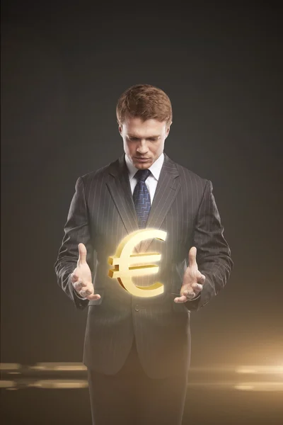 Young businessman chooses a Gold Euro Sign. — Stock Photo, Image