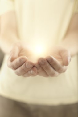 Male hands holding rays of glowing light. clipart