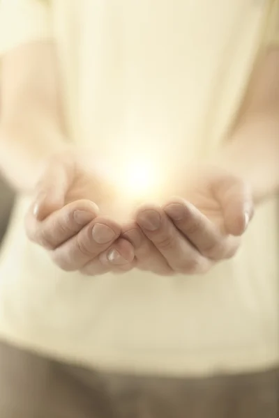 Männliche Hände, die Strahlen glühenden Lichts halten. — Stockfoto