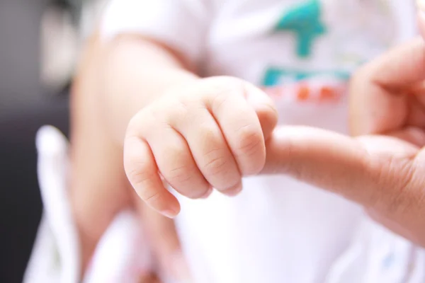 Детская рука, держащая палец матери — стоковое фото