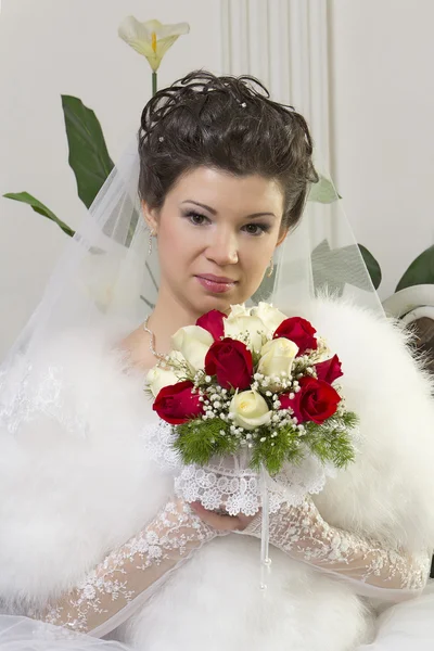 Bruid in een ontwerper jurk bedrijf een roos boeket — Stockfoto