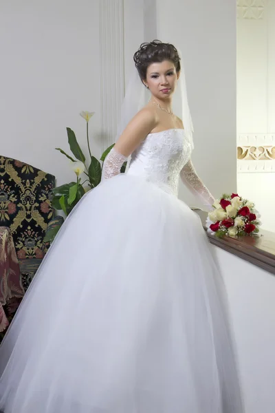 Noiva em um vestido de designer segurando um buquê de rosas — Fotografia de Stock