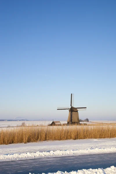 Mulino a vento in inverno con neve, ghiaccio e cielo azzurro — Foto Stock