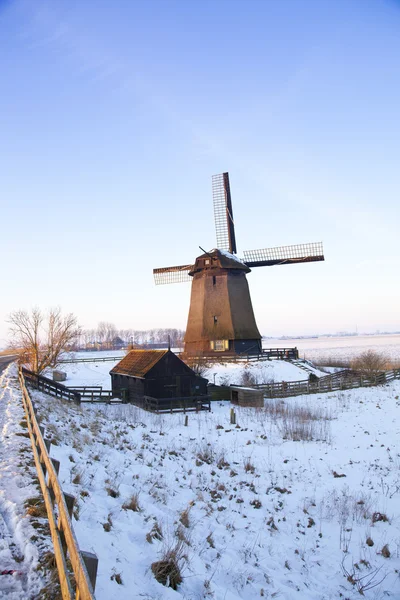 Ветряная мельница зимой со снегом и голубым небом — стоковое фото