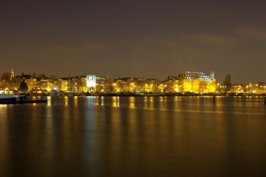 Amsterdam tarihi binaları ve tekne ile gece manzarası