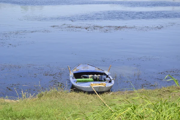 Oude roeiboot afgemeerd aan de rivieroever van een — Stockfoto