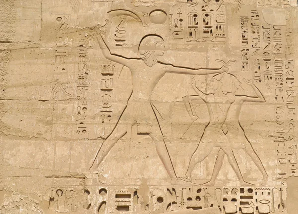 Sculptures hiéroglyphiques égyptiennes sur un mur Photos De Stock Libres De Droits