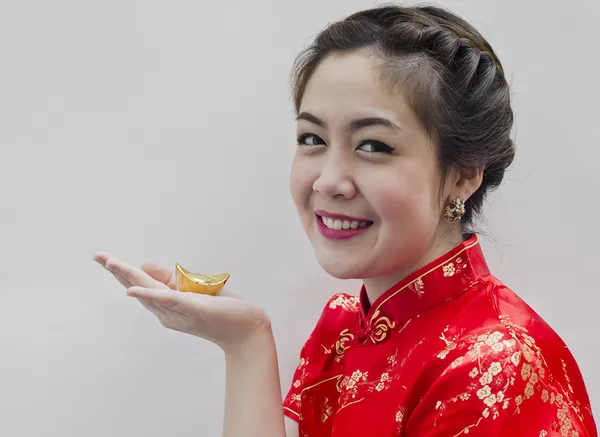Vacker asiatisk kvinna bära cheongsam och hålla kinesiska guld — Stockfoto
