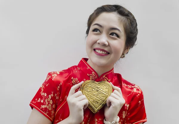 Vacker asiatisk kvinna bära cheongsam och hålla gyllene hjärta — Stockfoto