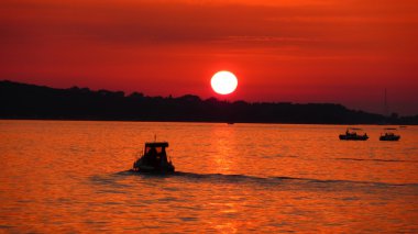 Fishermen on sea at red sunset clipart