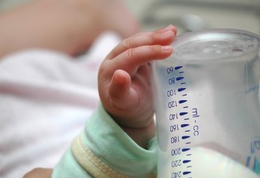 Baby holding his own milk bottle (*Slight grain) clipart