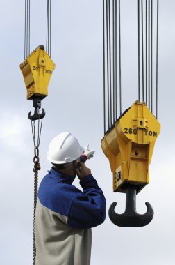 Crane hooks and building worker speaking on his phone clipart