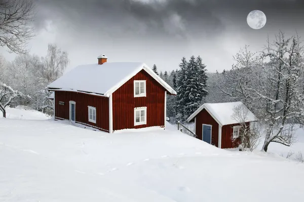 Red houses in snow forest under full moon Royalty Free Stock Images