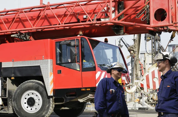 Trabalhadores da construção civil e guindaste móvel vermelho gigante — Fotografia de Stock