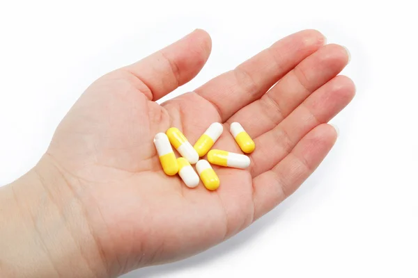 Cápsulas farmacêuticas na mão feminina sobre um fundo branco . — Fotografia de Stock