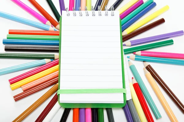 Notepad on a background of colored pencils. — Stock Photo, Image