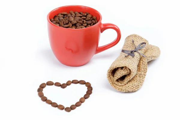 Corazón hecho de granos de café alrededor de una taza de café en una w — Foto de Stock