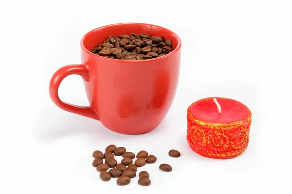 Grains de café dans la tasse et une bougie sur un fond blanc . — Photo