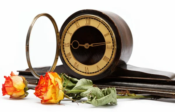 Antico orologio da tavolo in legno e fioriture su sfondo bianco . — Foto Stock