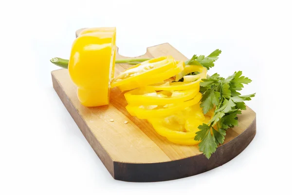 Gele peper en peterselie op een houten bord geïsoleerd. — Stockfoto