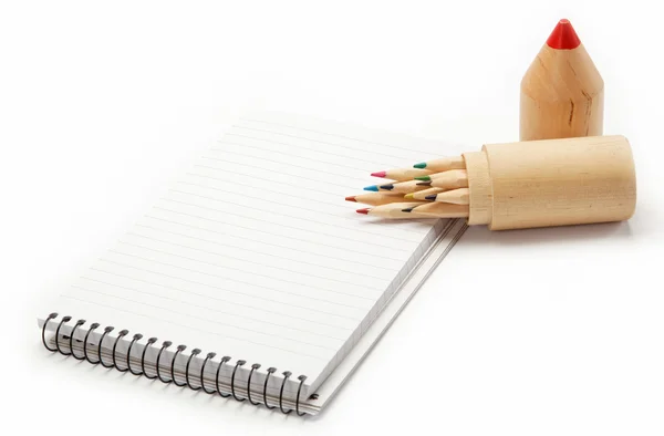 Lápis coloridos em uma caixa de madeira e um caderno em branco . — Fotografia de Stock