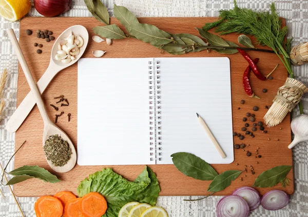 Ноутбук для рецептов и специй на деревянной доске — стоковое фото