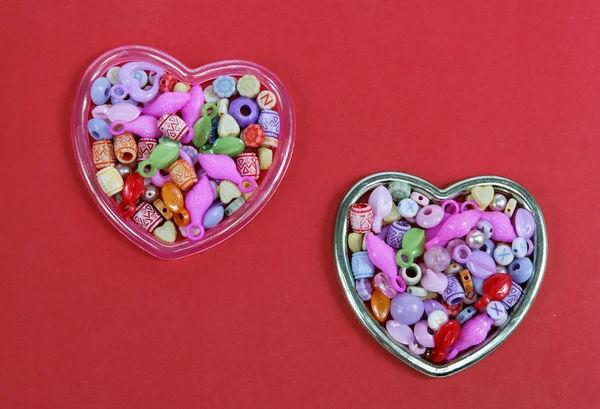 Two hearts from colored beads on a red background — Stock Photo, Image