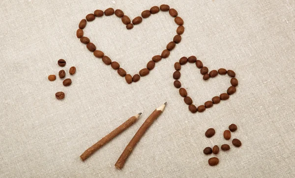 Kahve çekirdekleri ile keten kumaş ahşap bir kurşun kalemle iki kalp — Stok fotoğraf