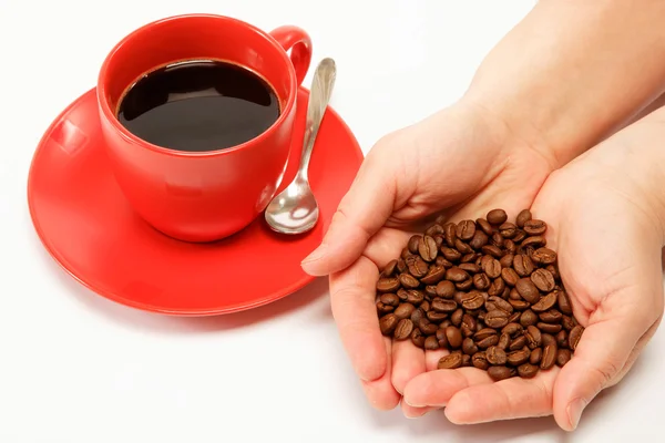 Coeur à la main fabriqué à partir de grains de café autour d'une tasse de café — Photo