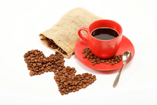 Dos corazones hechos de granos de café alrededor de una taza de café o —  Fotos de Stock