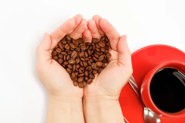 Corazón en mano hecho de granos de café alrededor de una taza de café — Foto de Stock
