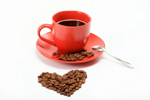 Corazón hecho de granos de café alrededor de una taza de café en una w —  Fotos de Stock