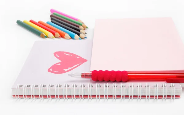 Notebook a barevné tužky na bílém pozadí. — Stock fotografie