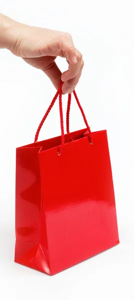 白い背景の上の女性の手で赤いギフト バッグ. — ストック写真