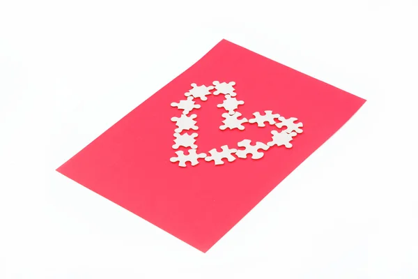 Puzzles in the shape of a heart on a red background. — Stock Photo, Image