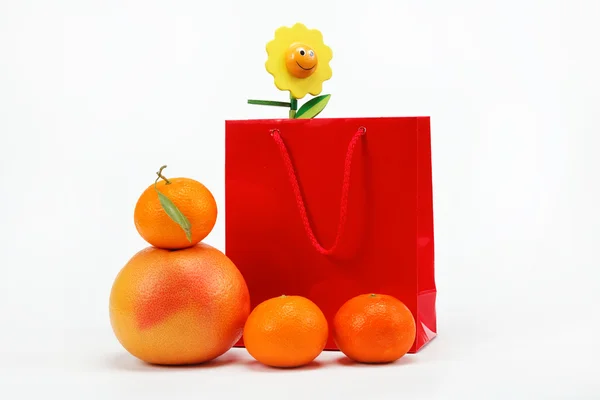 红色礼品袋和柑橘类水果在白色背景上. — 图库照片