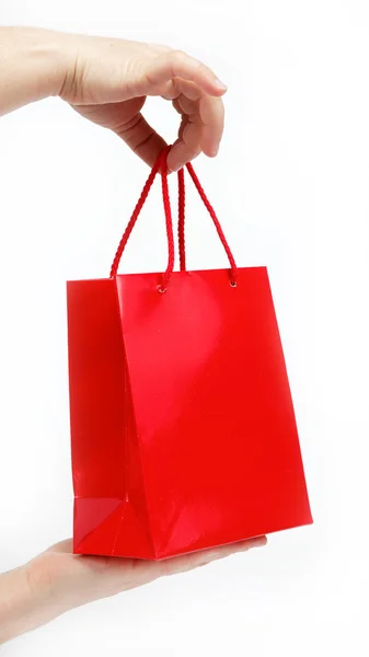 Красный подарочный пакет в руках женщин на белом фоне . — стоковое фото