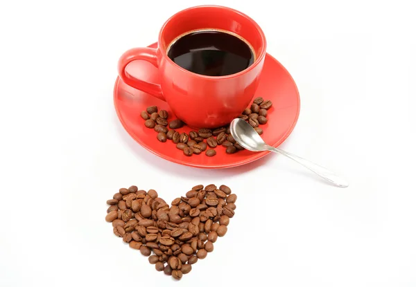 Corazón hecho de granos de café alrededor de una taza de café en una w — Foto de Stock