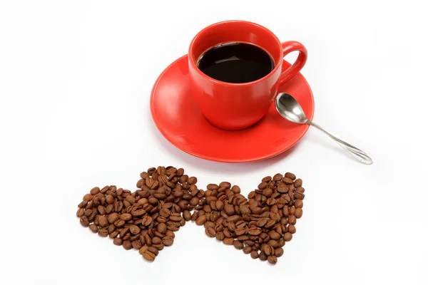 Corazón hecho de granos de café alrededor de una taza de café en una w —  Fotos de Stock