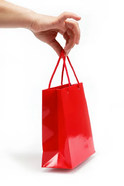 Röda gåva väska i damernas handen på en vit bakgrund. — Stockfoto