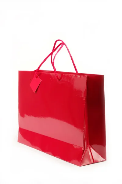 Красный подарочный пакет в руках женщин на белом фоне . — стоковое фото