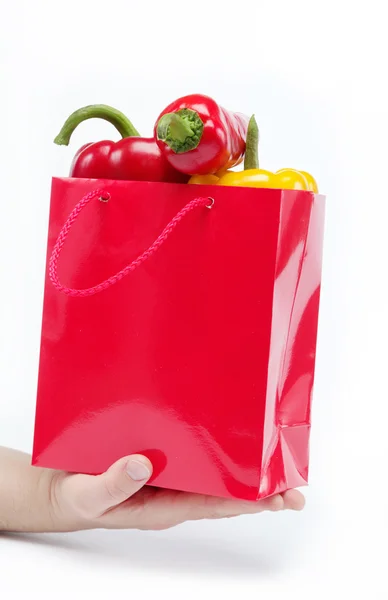 Fresh vegetables. Red gift bag in the women's hands on a white b — Stock Photo, Image