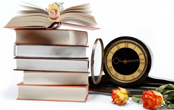 A stack of books and antique clock on a white background. — Stock Photo, Image