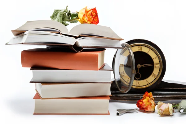 Una pila de libros y un reloj antiguo sobre un fondo blanco . —  Fotos de Stock