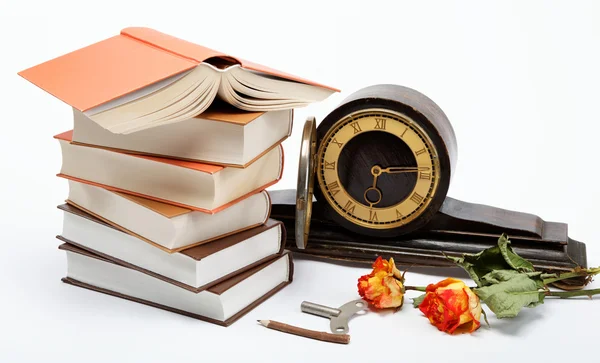 Egy halom könyvet és antik óra fehér alapon. — Stock Fotó