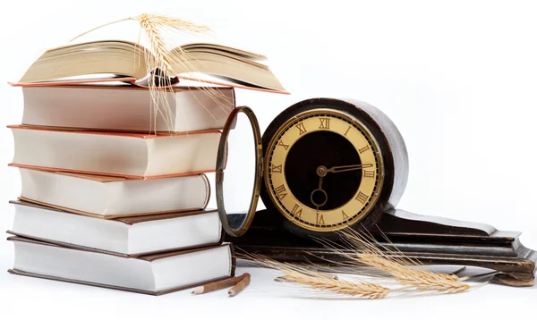 Una pila de libros y un reloj antiguo sobre un fondo blanco . — Foto de Stock