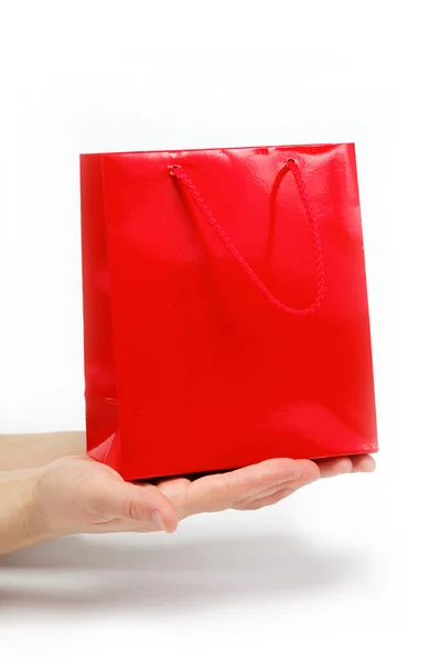 Saco de presente vermelho nas mãos das mulheres em um fundo branco . — Fotografia de Stock
