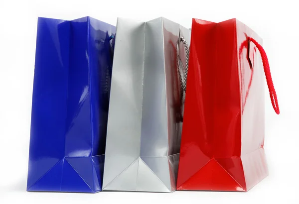 Beyaz zemin üzerine kırmızı, mavi ve gri hediye çantaları. — Stok fotoğraf