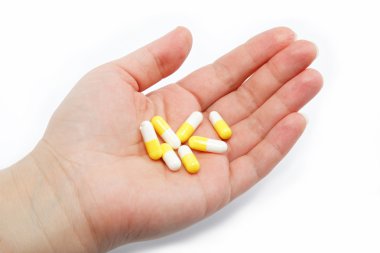 Pharmaceutical capsules in female hand on a white background. clipart