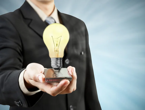 Businessman holding mobile phone light bulb coming out technolo — Stock Photo, Image